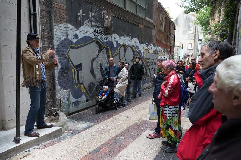 a man leans back as he tells a story to a crowd