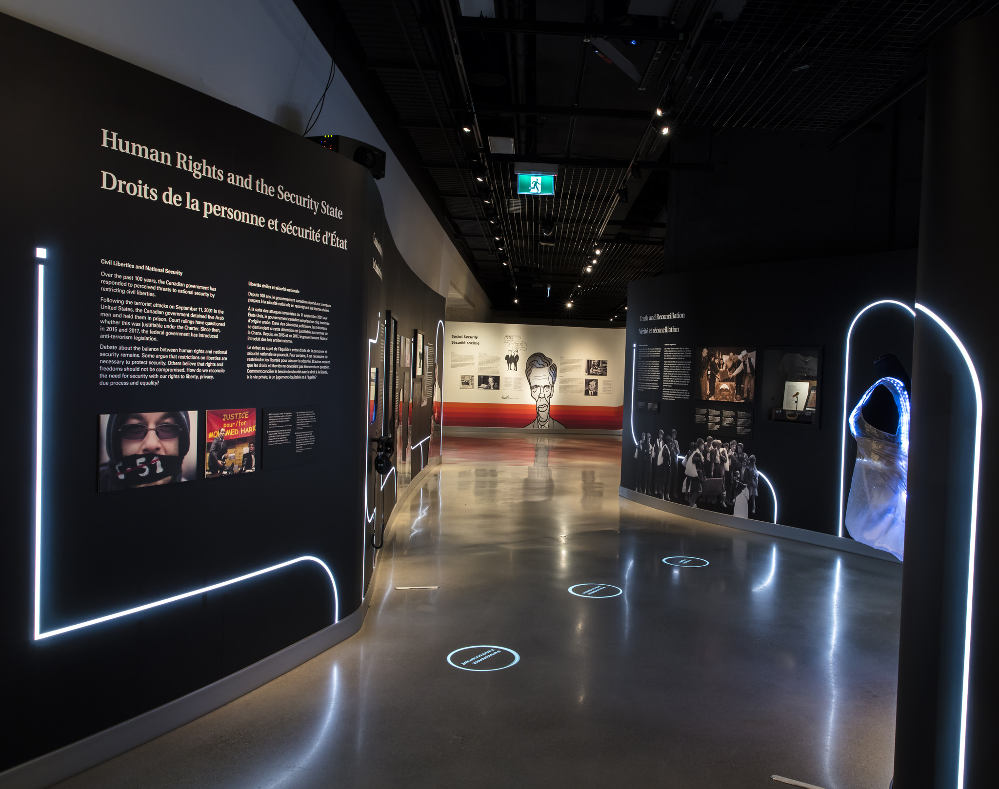 Three circles of light on the center of a cement floor, surrounding by wall featuring exhibition text.