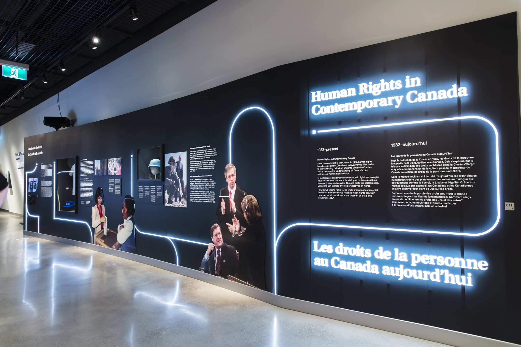 An elongated curved wall stretches from the bottom right to the top left. The wall is made up of text and images that are lit from behind.