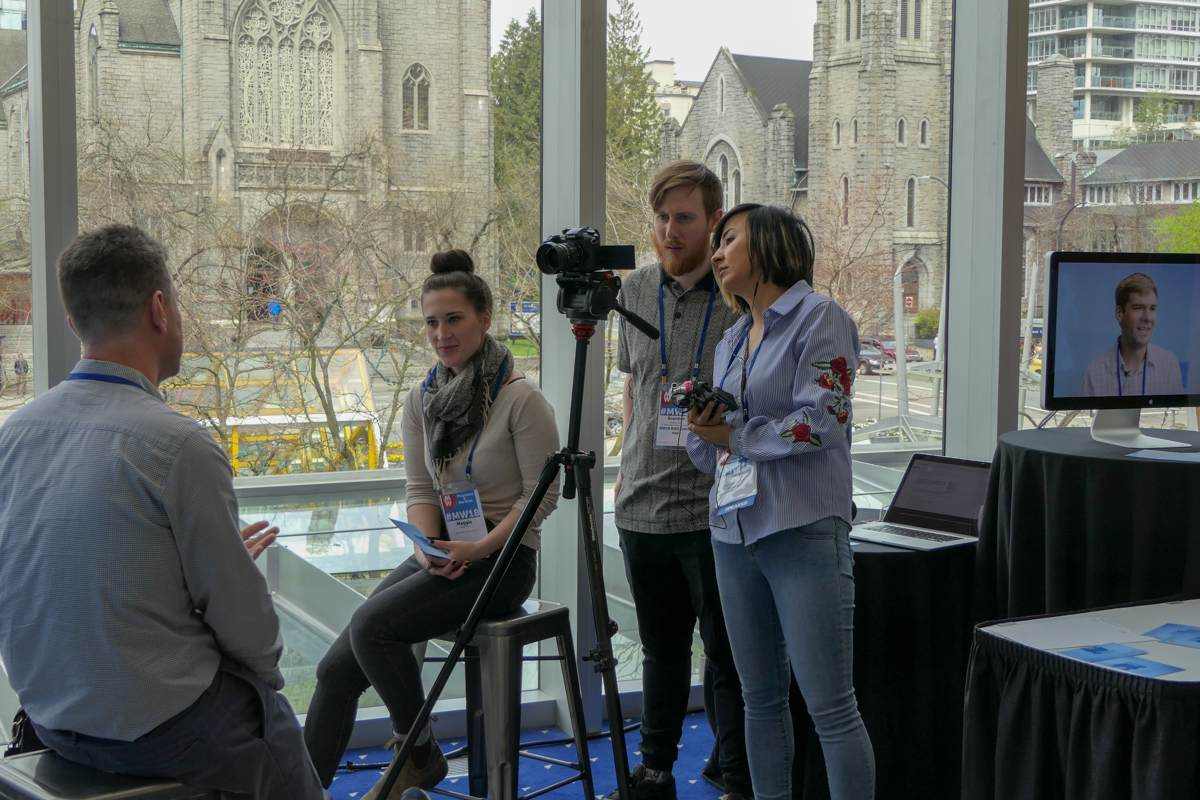 A group of three people record audio and video in a hallway at MW18.